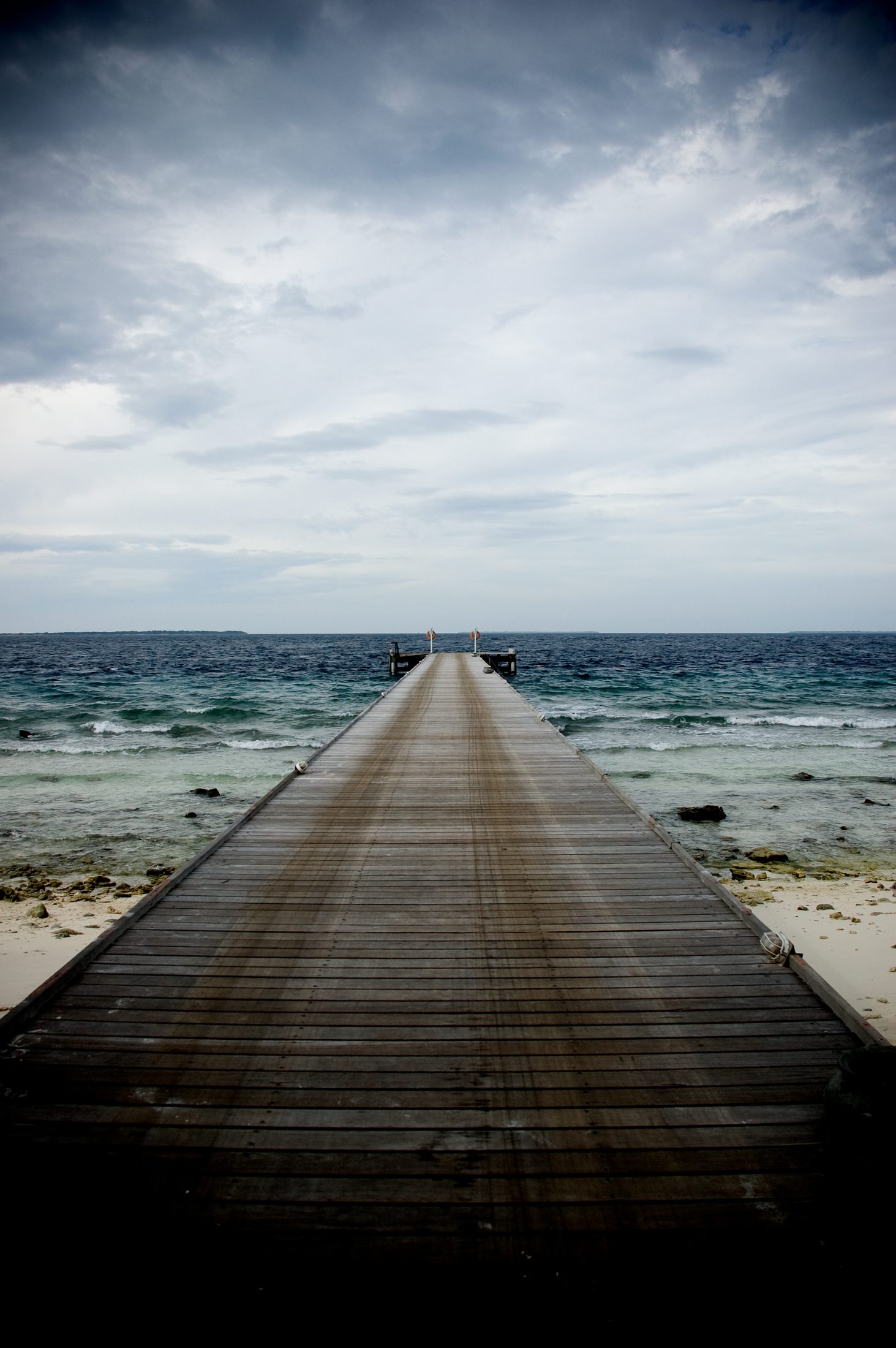 A wooden jetty running out to open sea under heavy cloud